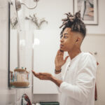 Man in the bathroom washing his face, symbolizing the importance of daily skincare and the use of acne medications for clearer skin.