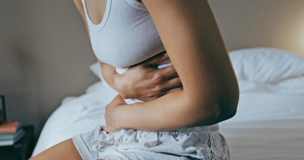 A person holding their stomach in discomfort, representing the common symptoms of constipation caused by Wegovy® and emphasizing the importance of dietary adjustments, hydration, and exercise to manage side effects.