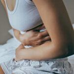 Woman holding her stomach in pain, symbolizing the discomfort of UTI symptoms and the importance of seeking treatment and care.